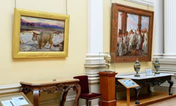 Framed painting of a white goat in a barren landscape hanging on the gallery wall